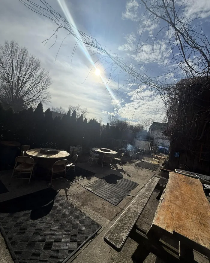 The back patio with picnic tables and fire-pit tables under an afternoon sky